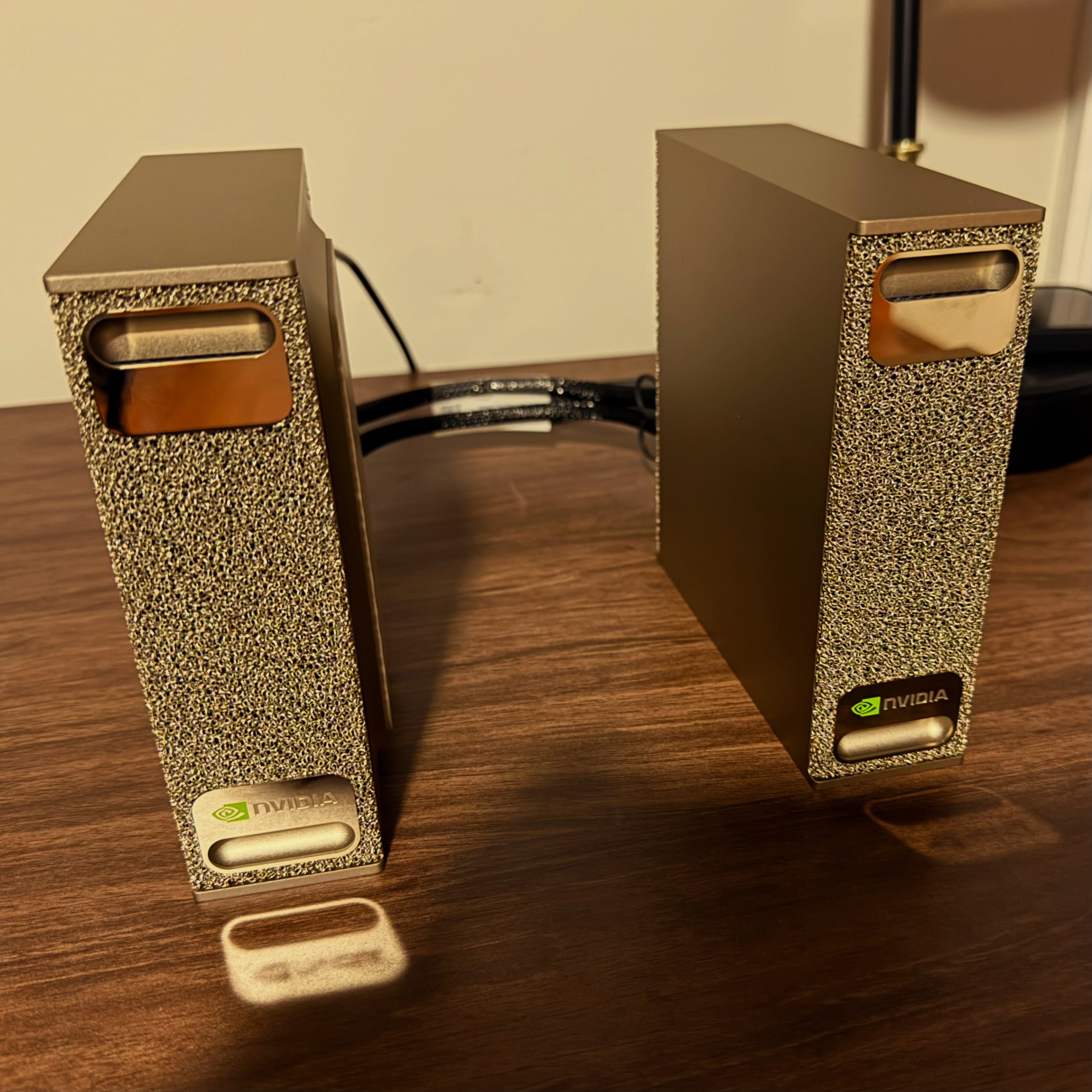 Two NVIDIA DGX Spark units facing each other on a desk, joined by a QSFP cable